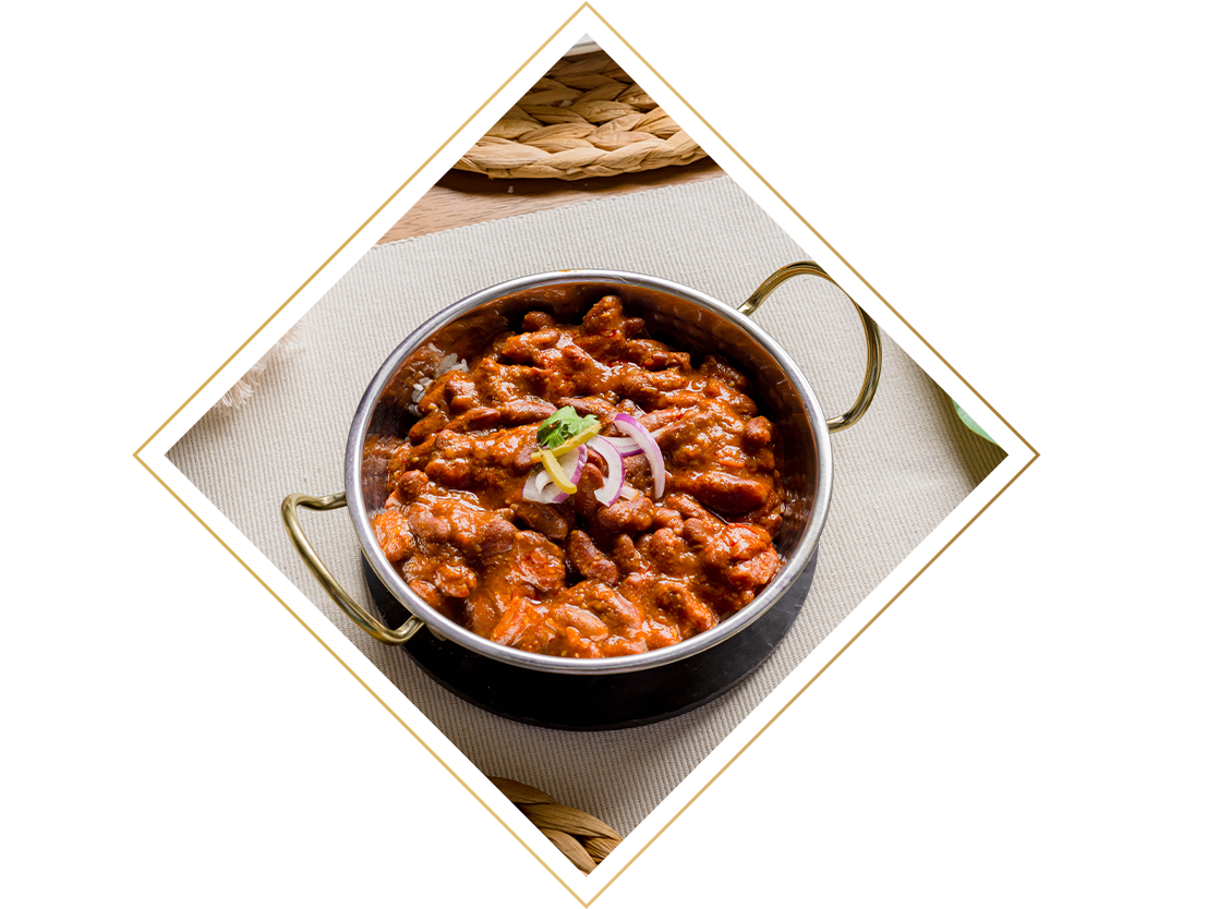 A close, up top down picture of the Raasa Majestic Red Bean curry. It looks creamy and indulgent and it is garnished with red onion, coconut slivers and a coriander sprig